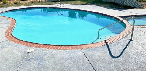 Stairs and railing enter swimming pool with bright blue water, a smaller pool to the right surrounded by grass. at Talavera, Boise, Idaho